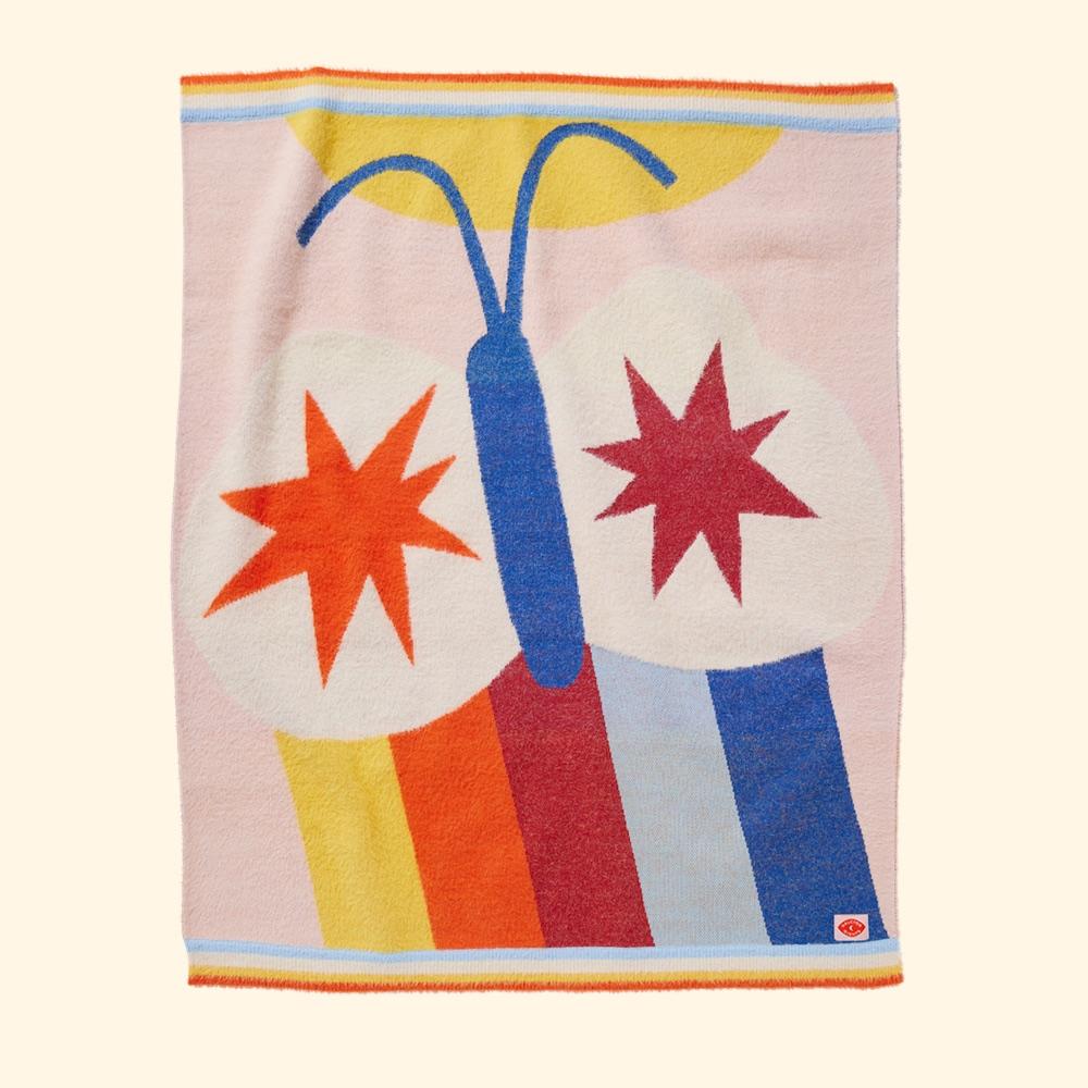Halcyon Nights Flutterby fluffy knit baby blanket with a blue butterfly, orange and red stars and rainbow stripes on a pale pink ground