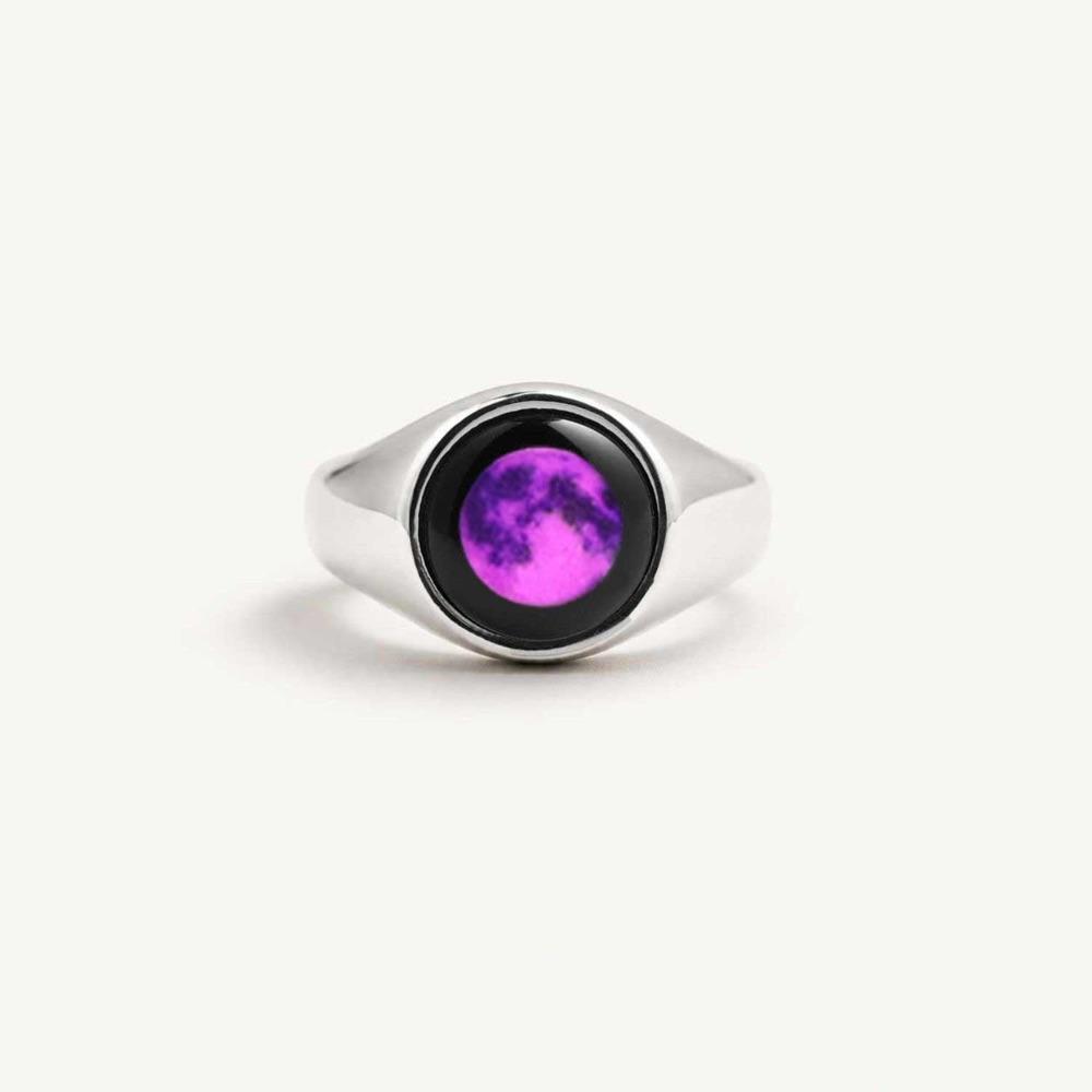 Silver Moonglow ring with a round black setting holding a bright purple moon, on a cream background
